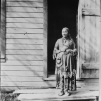 Woman Standing on Doorstep of Wooden Building