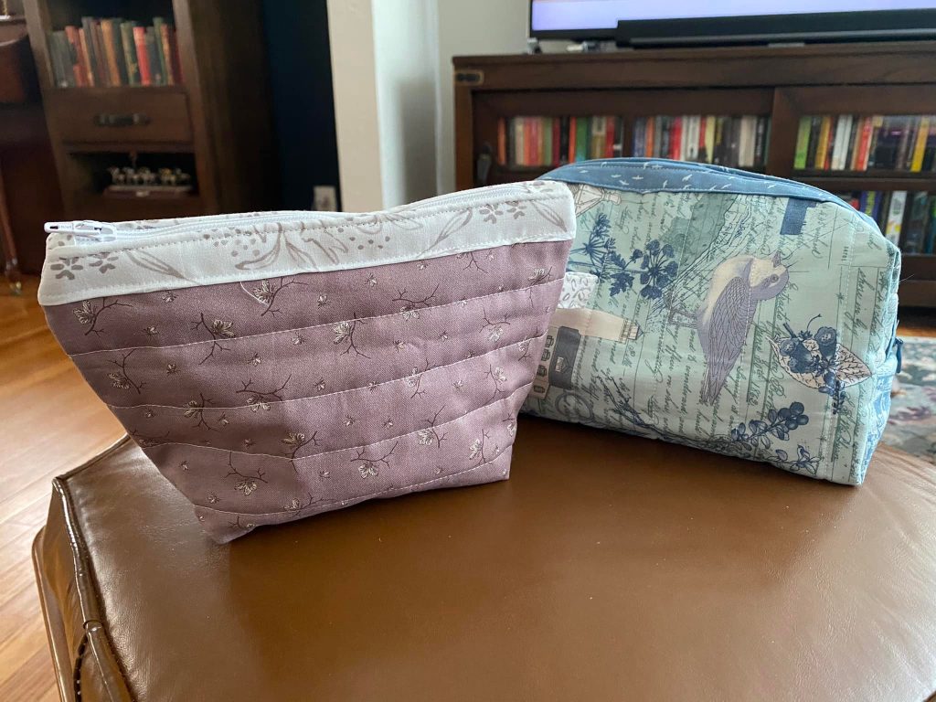 Photo of two quilted pouches, one a lilac and white makeup bag and the other a blue and teal medicine bag